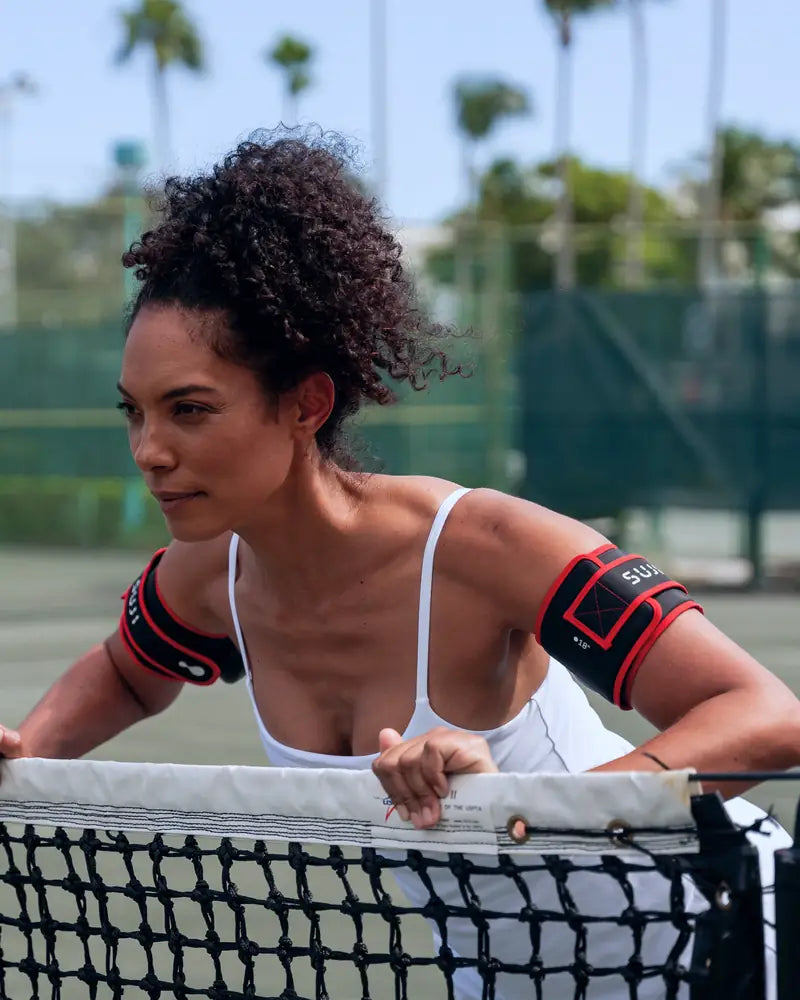 A person leaning forward into a push-up position, wearing a Suji cuff on each upper arm.