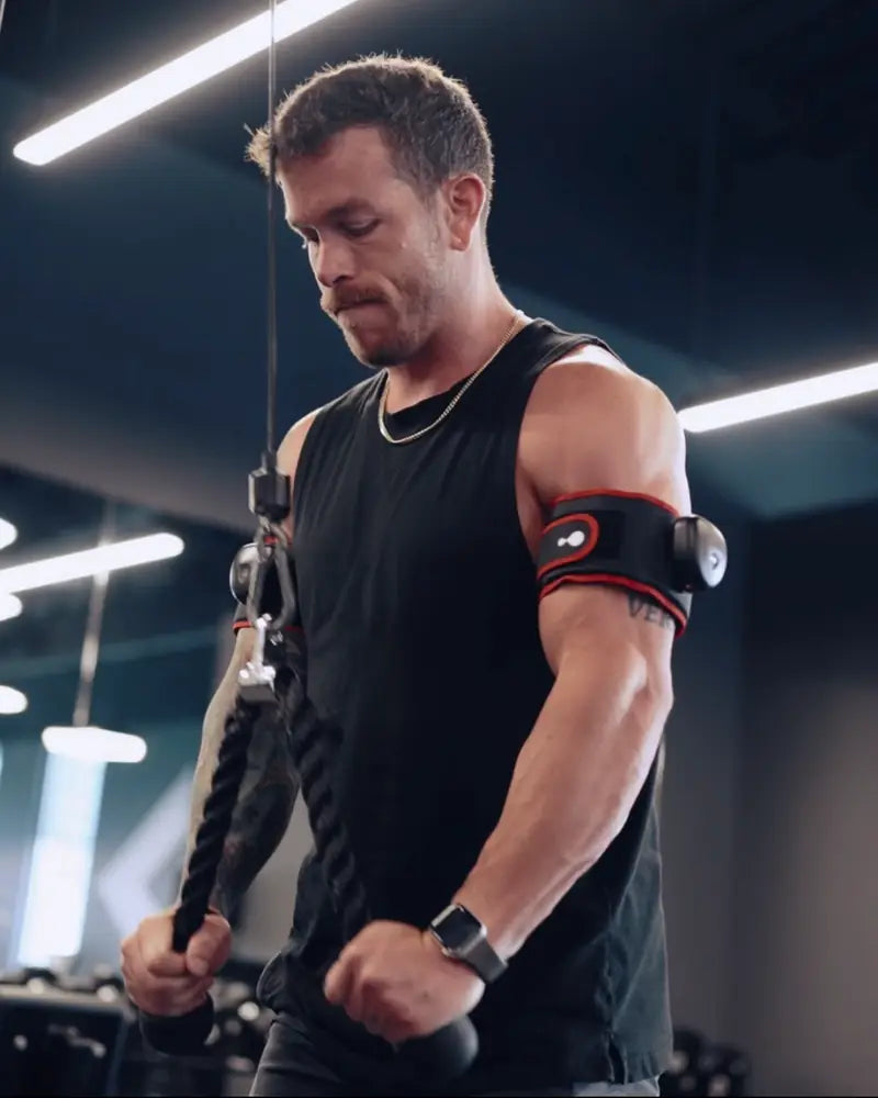 A person in a gym wearing a Suji cuff on the upper arm.
